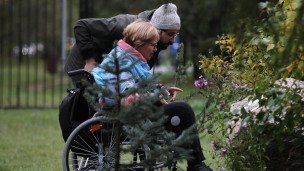 Женщина в инвалидном кресле смотрит на цветы