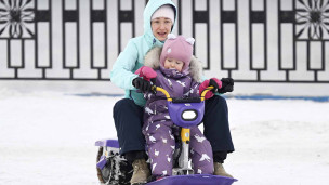 Женщина с ребёнком катаются на снегокате