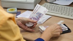 Сотрудница банка выдает ежемесячное денежное пособие
