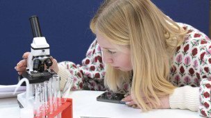 девушка смотрит в микроскоп