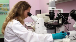 Научный сотрудник смотрит в микроскоп