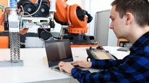 IT-специалист проверяет работоспособность робота для промышленных целей в лаборатории 