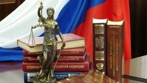 Статуя Фемиды и юридическая литература на столе в зале судебных заседаний