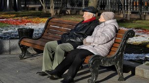 Пожилые люди сидят на скамейке в сквере