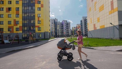 Женщина с ребенком в коляске в жилом комплексе