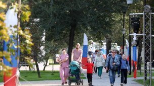 Семья гуляет в праздничный летний день в городе