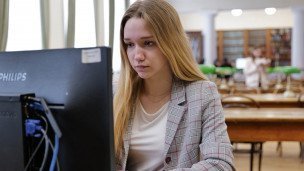 Студентка за компьютером в читальном зале