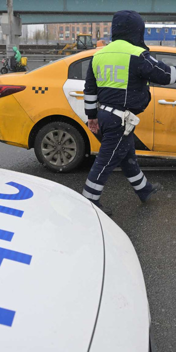 Сотрудник ГИБДД проверяет документы у водителя такси