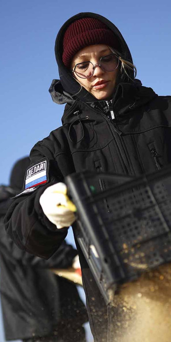 девушка просеивает песок на пляже, где произошел разлив мазута