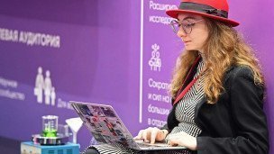 Девушка в очках сидит за ноутбуком