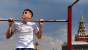 Молодой человек подтягивается на турнике