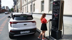 Девушка заряжает электромобиль 