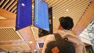 Мужчина смотрит на табло в аэропорту