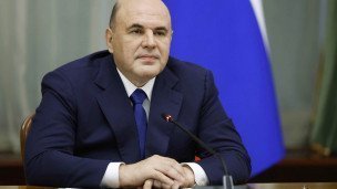 Председатель правительства РФ Михаил Мишустин сидит за столом сзади флаг России