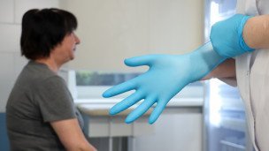 Медсестра надевает перчатку 