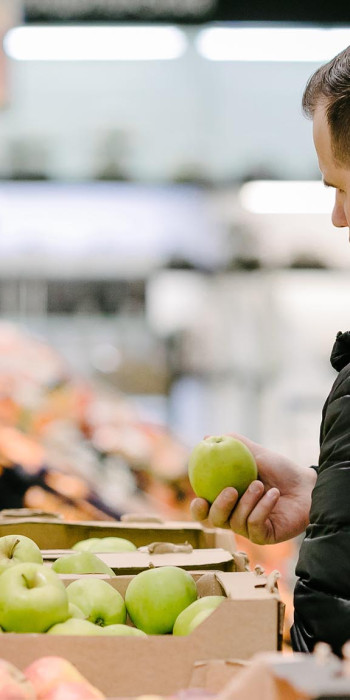 Покупатель у лотка с яблоками в магазине 