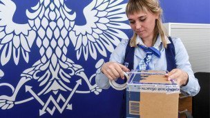 Сотрудница почты упаковывает посылку
