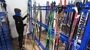 Молодой человек выбирает комплект беговых лыж