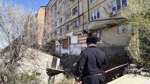 полицейский возле пострадавшего от паводков дома