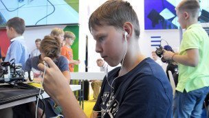 Школьник в наушниках со смартфоном в руках