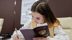 Сотрудница помогает заполнить документы клиенту