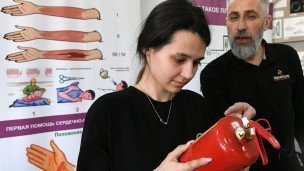 ученица рассматривает огнетушитель на уроке обж
