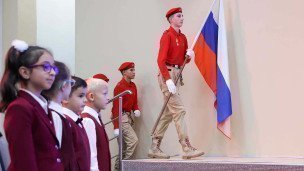 Школьники во время линейки выносят флаг России