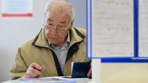 Пожилой мужчина заполняет документы