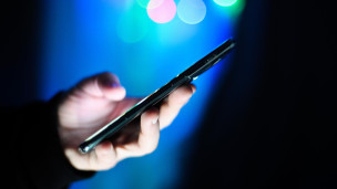 Мужчина держит в руках мобильный телефон