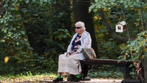 Пожилая женщина на скамейке в парке