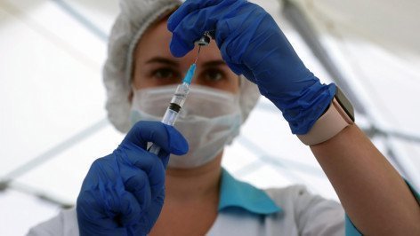 Медицинский работник набирает в шприц вакцину