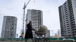 Женщина с коляской у строящихся жилых домов на улице 