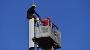 Рабочие монтируют базовую станцию сотовой связи.