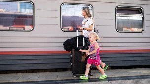 Женщина с ребенком и чемоданом около поезда