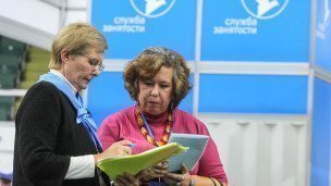 Пожилой посетительнице помогает сотрудница ярмарки вакансий