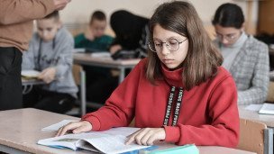 Ученица средней школы читает во время урока