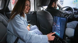 Пассажирка в салоне такси выбирает маршрут на экране планшета 