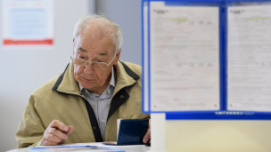 Пожилой посетитель заполняет документы 