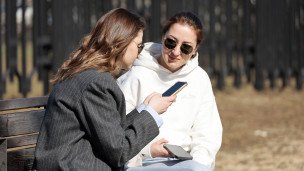 Девушки со смартфонами в парке 