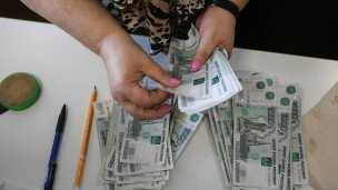 Сотрудница пересчитывает купюры номиналом тысяча рублей