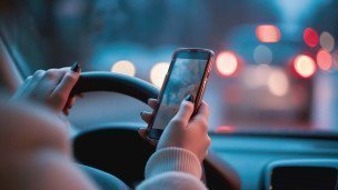  Водитель за рулем со смартфоном в руке