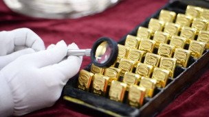 Рабочий рассматривает золотые слитки