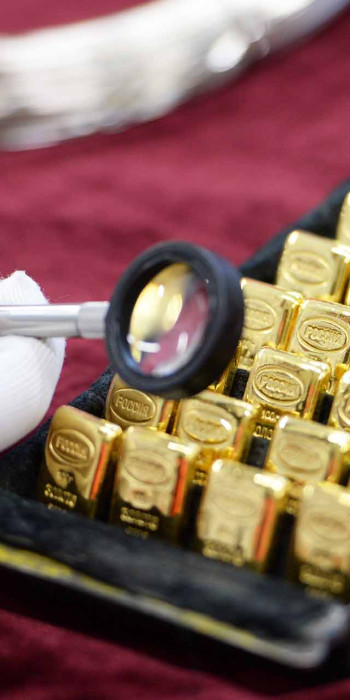 Рабочий рассматривает золотые слитки